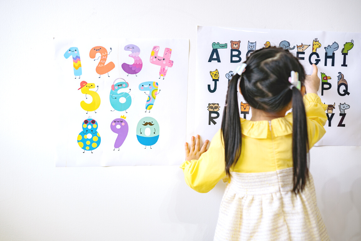 Woman in Yellow Long Sleeve Shirt Standing in Front of White Wall With Assorted Stickers